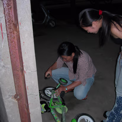 National_Day_2005-001 Xiaohua repairing Ben's trike outdies the beer patio.