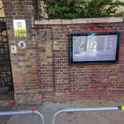 UK-2022-287 This is the Russian Embassy gate. All blocked off but still covered with red paint. The barriers have the Ukrainian colors on them as well.